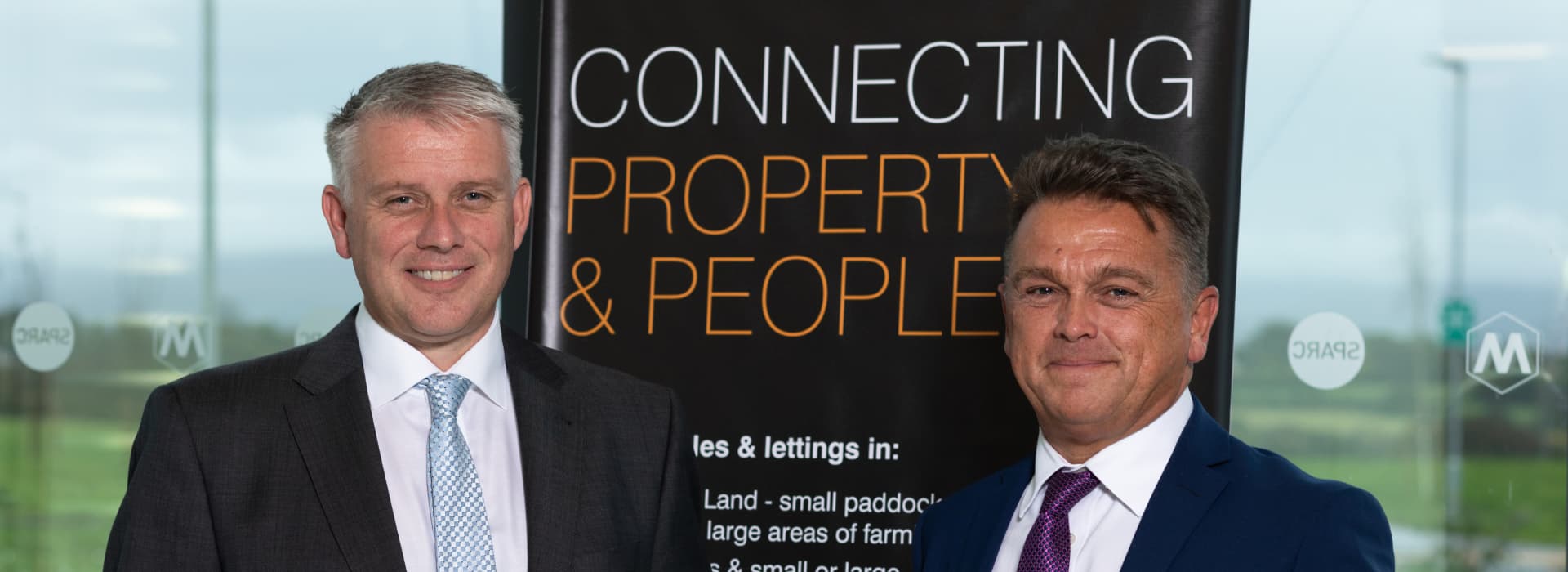 Melfyn and Tim of Williams and Goodwin The Property People, standing in front of a connecting property people banner.